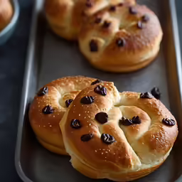 a tray with four rolls and chocolate chip toppings on top