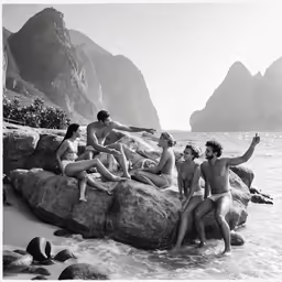 a group of men and women sitting on top of large rocks in the water