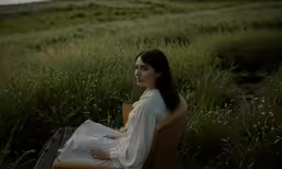 a woman sitting in an armchair on the grass