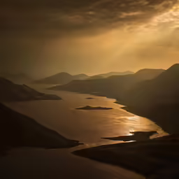 the sun shining in over water from mountains