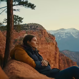 a woman is sitting on a rock ledge
