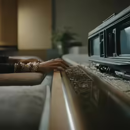 two hands hold something near a television set