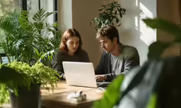 two people sitting at a table with a laptop computer