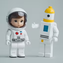 two legos standing next to each other in front of a wall