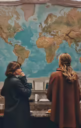 a man and woman standing near a map on a wall