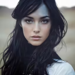 a woman with black hair standing in the grass
