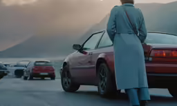a woman stands by a car in a parking lot