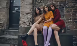 four girls sitting on a ledge in front of a building
