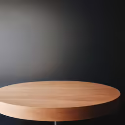 an oval wooden table sitting against a dark wall