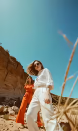 a woman in white shirt and pants on rocky terrain