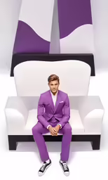 a man in purple suit sitting on a white chair