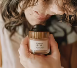 young woman looking at jar of cream