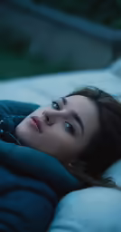 a beautiful young woman lying down in a blue jacket