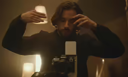 a man is looking into a camera in the mirror