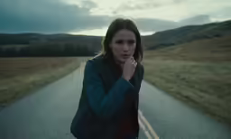 the woman stands in front of an empty road