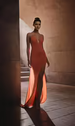a woman poses in an orange gown on the floor