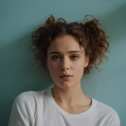 a young woman wearing white has her hand under her chin