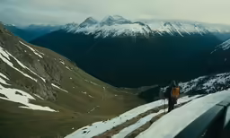 a man with backpack standing on a steep snowy hill