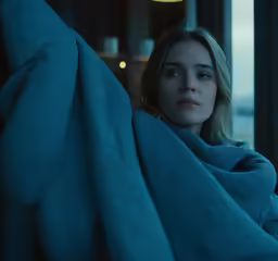 a woman with blue hair, wrapped in a blanket