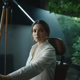 a woman sits in a chair while holding her arms on the ground