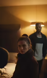 a man and woman standing in the bedroom together