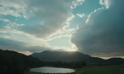 clouds hover over the river and mountains in the distance