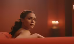a beautiful young lady laying down on a red couch