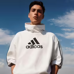 a man wearing a white adidas shirt with black logo on it