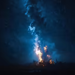 fire blazing in the night with smoke on the ground
