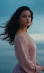 a woman in pink is standing near the water