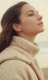 a girl standing near the water with her head turned