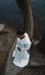 a person sitting on top of a rock near water
