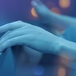 hands touching the surface of a water with lights in the background