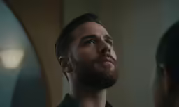 a young man stares into a mirror