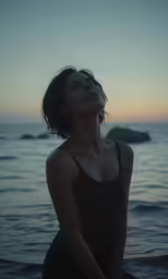 a woman in black shirt standing next to the ocean