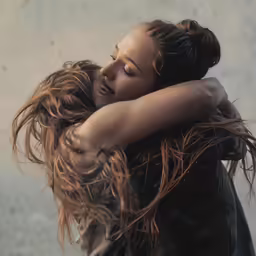 a woman with a frizzy brown hair embracing another woman
