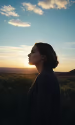 a woman is staring in to the distance at sunset