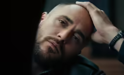 a man in black shirt holding his hand to his head