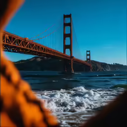 a view from behind a body of water in front of a bridge