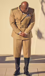 a man wearing a long tan suit and tie