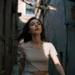 woman in white top standing in alley and looking upward