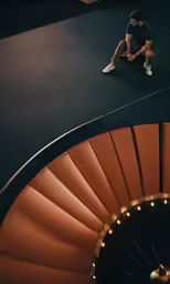 a man in a dark room with a spiral stair