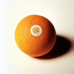 an orange with a button is shown sitting on the table