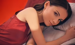 a woman laying in bed on top of a white pillow