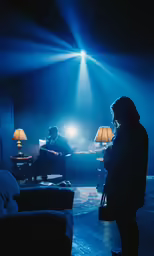 the person stands in a dark room with a lamp on