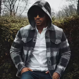 a man in a hooded jacket is sitting on the ground
