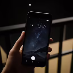 hand holding smart phone with black screen on night sky
