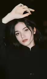 a young woman posing for a photograph while she has her hand on the top of her hair