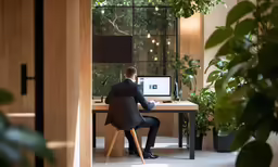 a man sits in front of his desk and looks at the screen