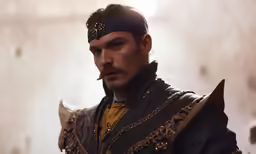 a man wearing armor, smoking and looking towards the camera